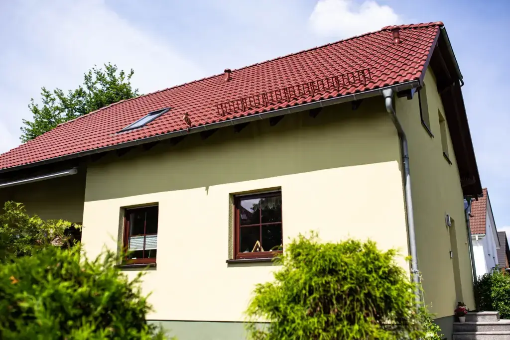 Frisch gestrichene Außenfassade eines Wohnhauses in hellem Farbton mit neuem Sockelbereich, professionell saniert von Malermeister Poitz in Bautzen.