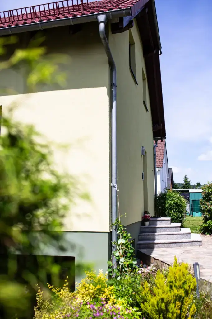 Seitenansicht der frisch gestalteten Hausfassade inklusive farblich abgesetztem Sockel und Treppenaufgang in der Oberlausitz.