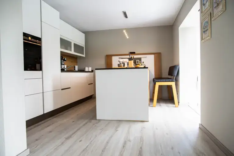 Blick in die renovierte K&uuml;che mit Fokus auf die harmonische Wandfarbe in Taupe und den neu verlegten Fu&szlig;boden.