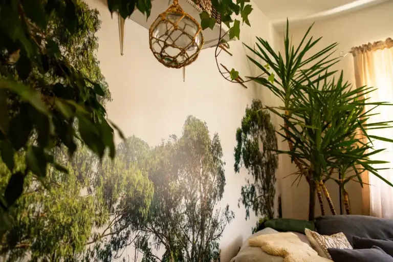 Detailansicht einer hochwertig tapezierten Fototapete mit Wald- und Baummotiv im Wohnzimmer, kombiniert mit echten Zimmerpflanzen.