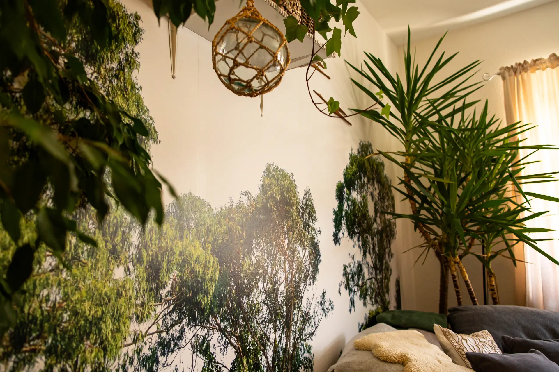 Detailansicht einer hochwertig tapezierten Fototapete mit Wald- und Baummotiv im Wohnzimmer, kombiniert mit echten Zimmerpflanzen.