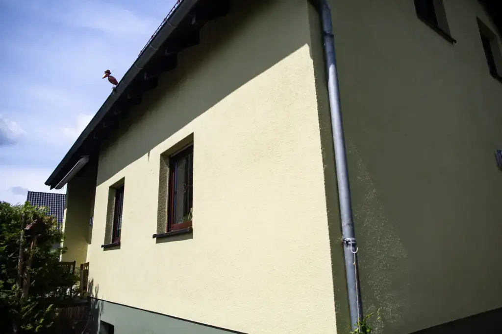 Blick von unten auf die rissfreie und wetterfest beschichtete Außenwand des Privathauses nach der Fassadensanierung in Ostsachsen.