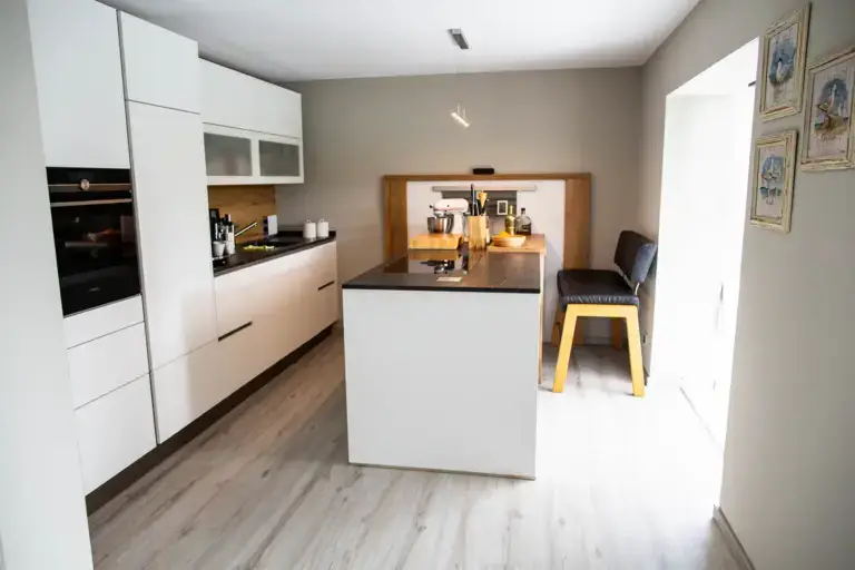 Blick in die renovierte K&uuml;che mit Fokus auf die harmonische Wandfarbe in Taupe und den neu verlegten Fu&szlig;boden.