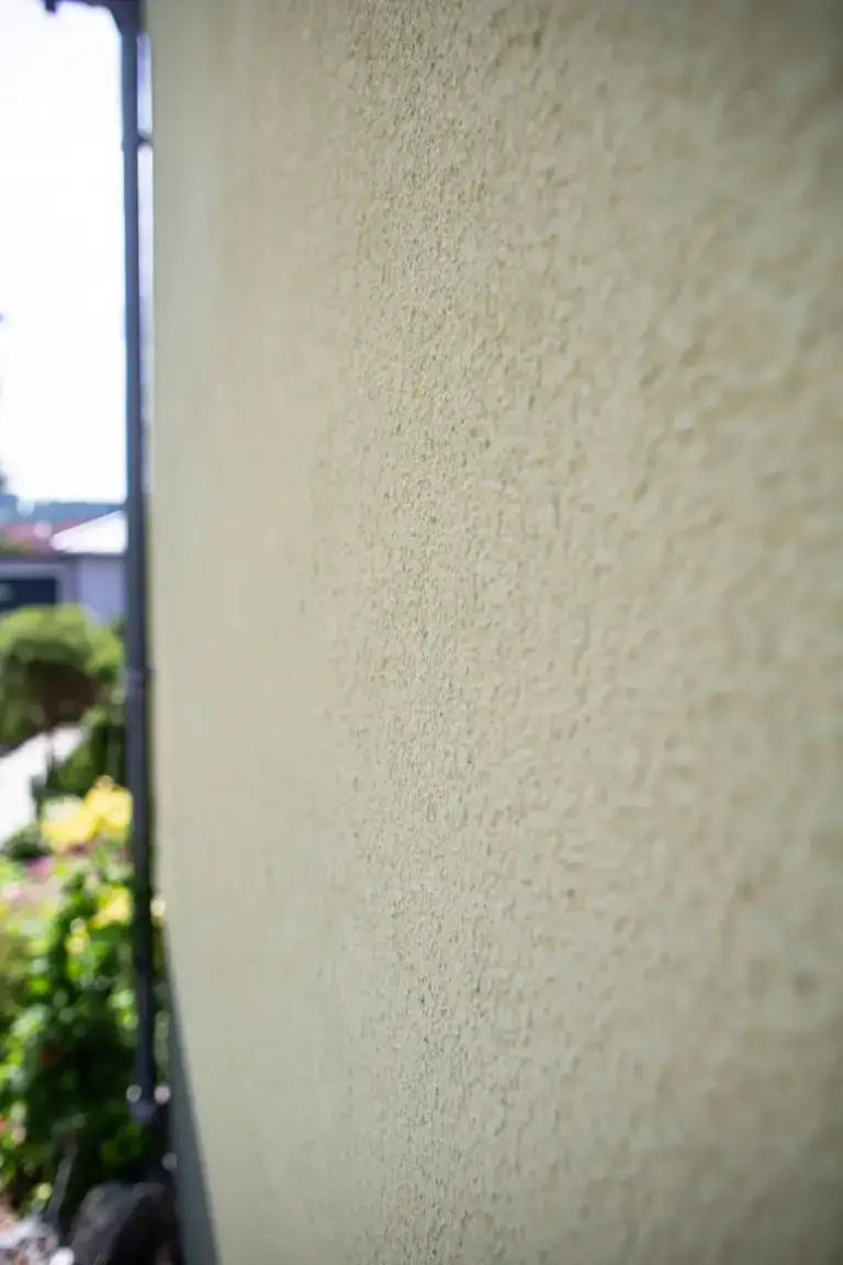 Detailansicht der Hausecke mit dem sauber abgegrenzten, grau-gr&uuml;nen Fassadensockel, ausgef&uuml;hrt von Malermeister Poitz.