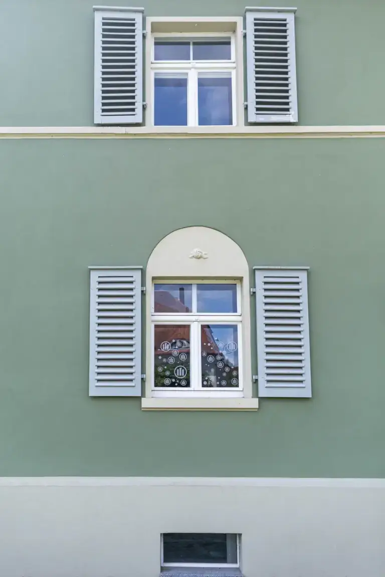 Blick von unten auf den Eingangsbereich der B&uuml;ro-Villa mit stilvoller Au&szlig;enleuchte und historischer Architektur.