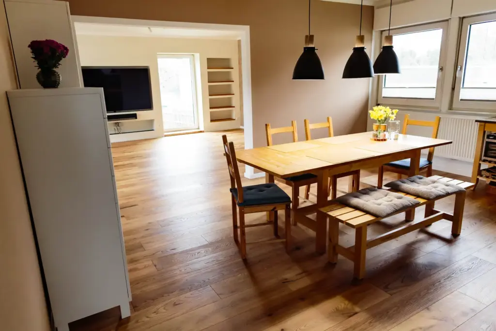 Essbereich mit Sideboard und Blumenvase, Blick durch den Durchbruch ins Wohnzimmer