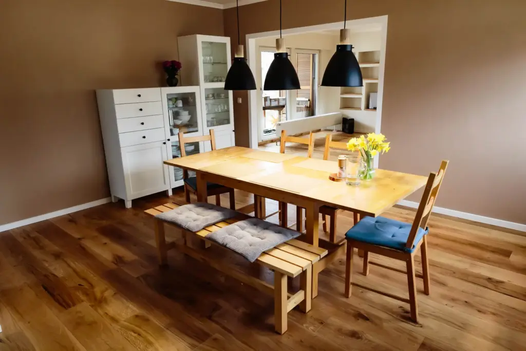 Essbereich nah am Tisch mit Sideboard, Vitrine und Blumen unter den Pendelleuchten