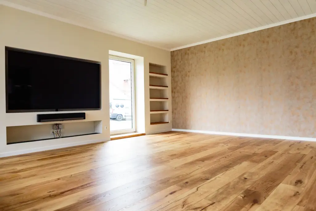 Leeres Wohnzimmer mit TV-Wand und offener Regal-Nische vor der Neugestaltung